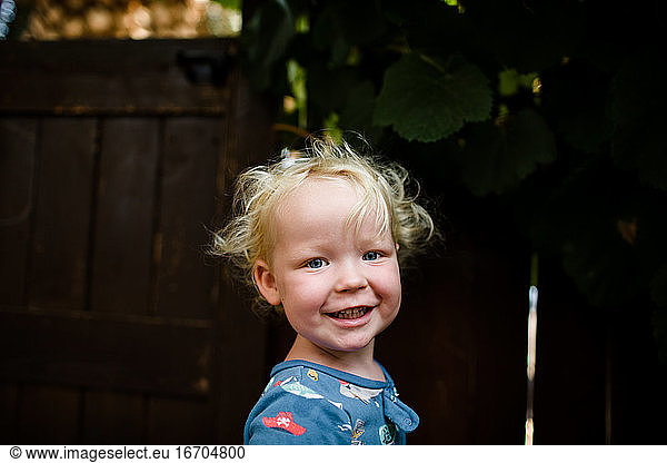 Blond Two Year Old Boy Smiling for Camera Standing in Yard