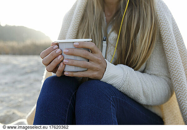 Blond woman in warm clothing holding tea cup