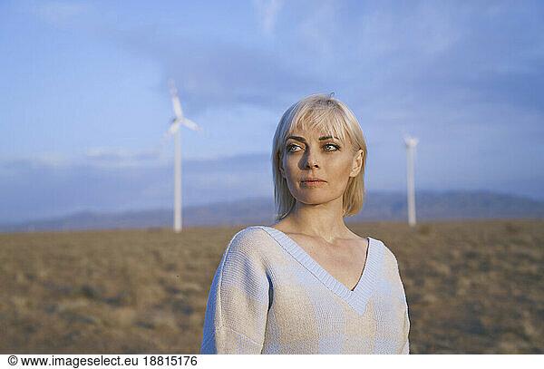 Blond woman standing near wind turbines in desert