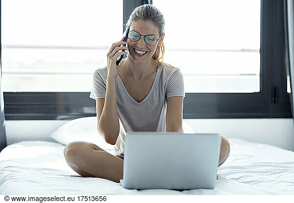 Blond woman using laptop and smartphone at home