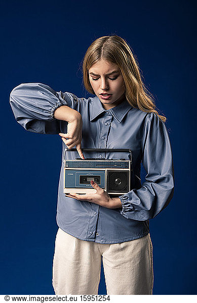 Blond woman with cassette player in front of blue background
