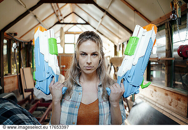Blond woman with toy guns in garage