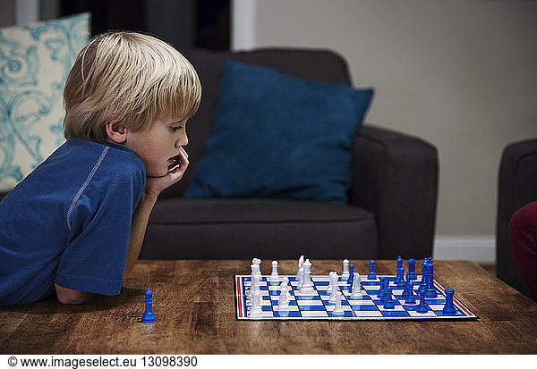 Blonde boy playing chess at table