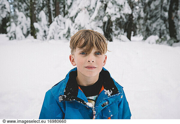 Blonde Boy With Blue Eyes Standing in a Snowy Field
