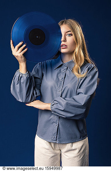Blonde Frau mit blauer Schallplatte vor blauem Hintergrund