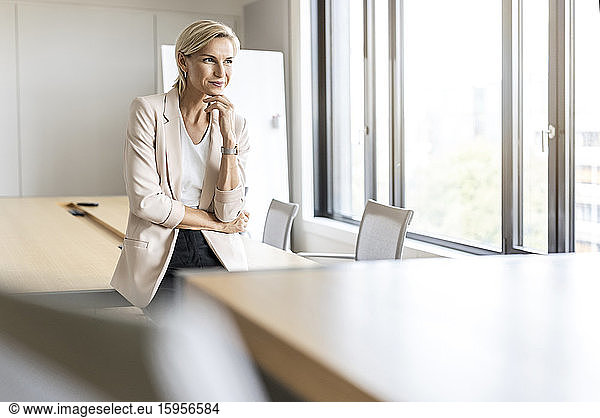 Blonde Geschäftsfrau im Konferenzraum denkt