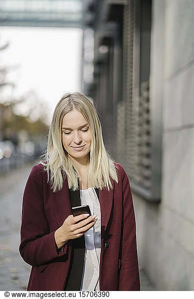 Blonde Geschäftsfrau mit Smartphone in der Stadt  Blick nach unten