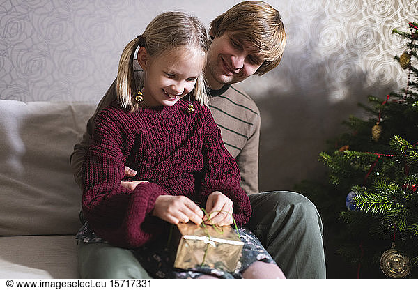 Blonde girl and opening Christmas present  Father behind her