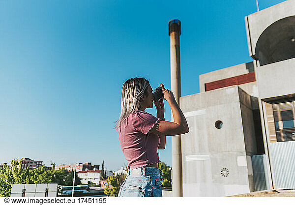 Blonde girl taking pictures of a building