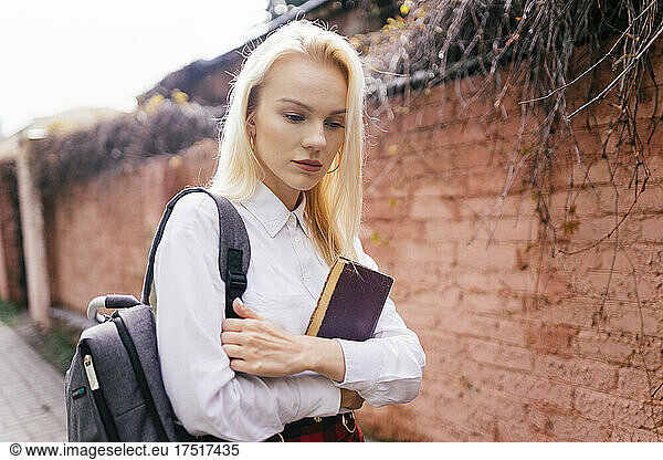 blonde girl walking with a book