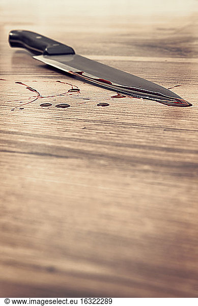 Blood stained knife on wooden floor