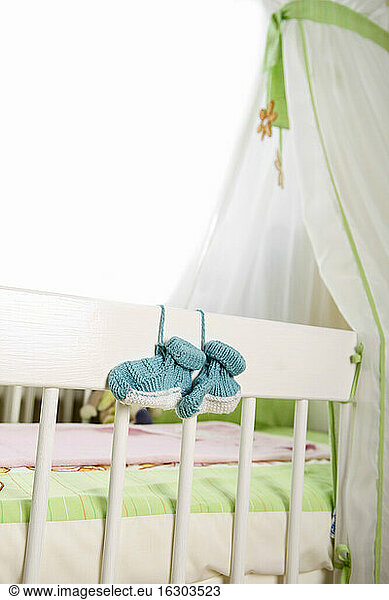 Blue baby shoes hanging to cot