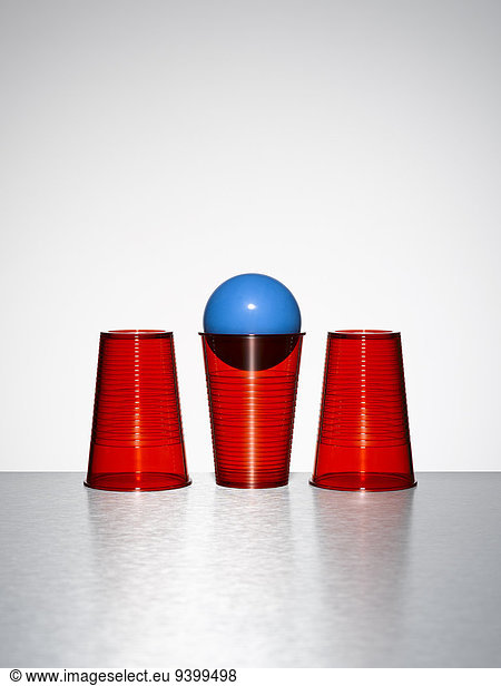 Blue ball in middle of three red cups