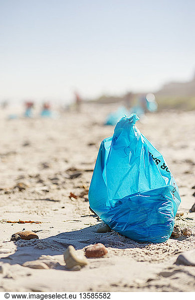 Blue cleanup garbage bag on sunny  sandy beach