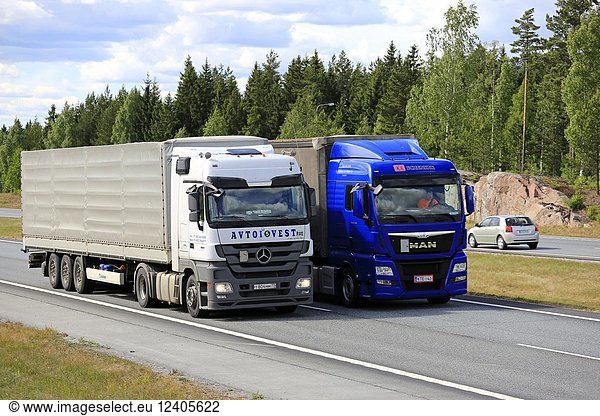 Blue MAN semi truck overtakes another truck on motorway in summer. Trucks with heavy cargo can be much slower uphill. Salo  Finland - June 8  2018.