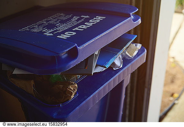 Blue recycling bin full of garbage