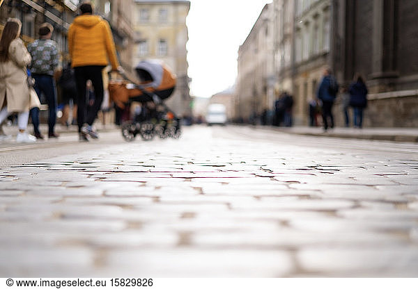 Blurred background of paving stones and people walking with baby buggy