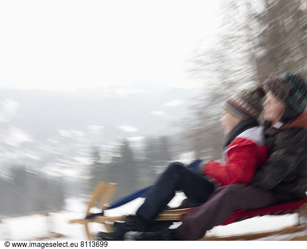 Blurred motion view of boys sledding in snow