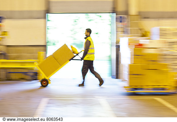 Blurred view of worker pushing boxes in warehouse