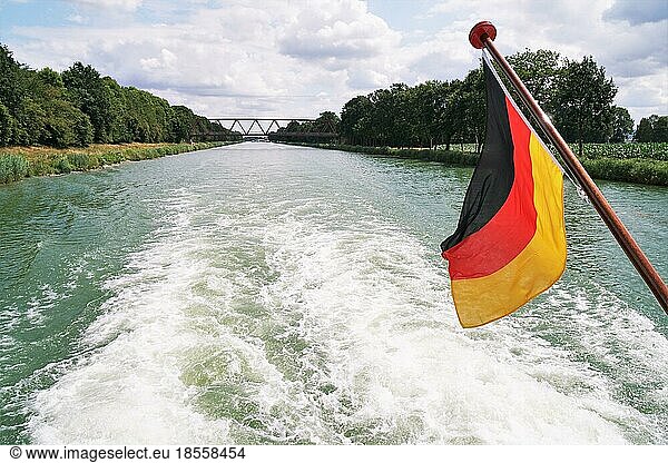 boat cruise on Mittellandkanal (midland canal) in Germany between the towns of Minden and Bad Essen - rear view with backwash wake and German flag