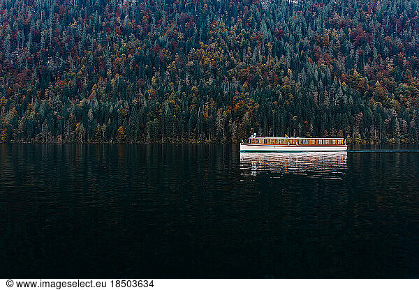 boat floats on the dark waters against the colorful forest