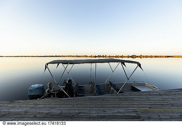 Boat moored at a jetty on the waters of the Okavango Delta at sunset  Botswana.
