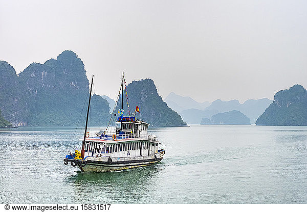 Boat passes through foggy karst landscape in Ha Long Bay  Vietnam