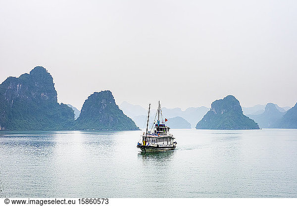 Boat passes through foggy karst landscape in Ha Long Bay  Vietnam