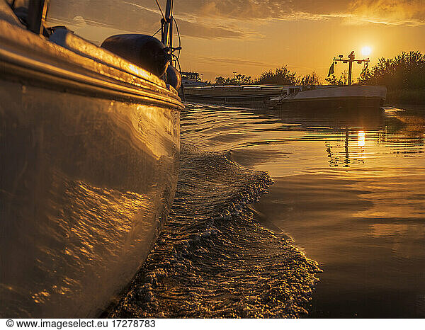 Boat sailing along Juliana Canal at sunrise with barge trailing behind