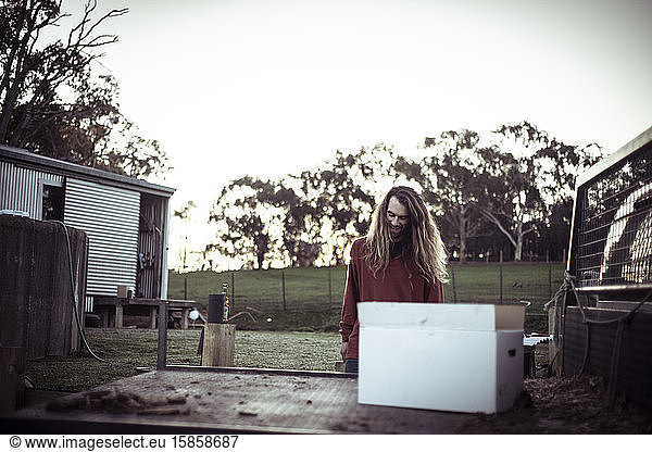 bohemian man with long hair and beard smiles at sunset on farm