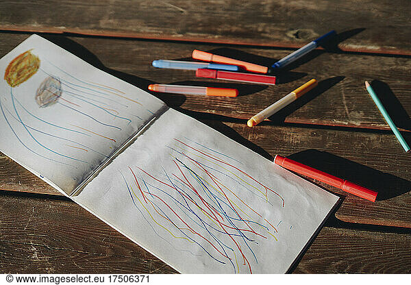 Book and colorful pen on wooden bench
