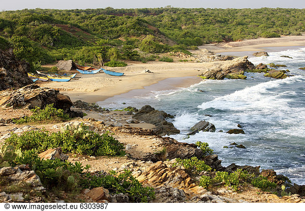 Boote einheimischer Fischer vor strohgedeckten Hütten am felsigen Strand vor Urwald Yala Nationalpark Sri Lanka Asien