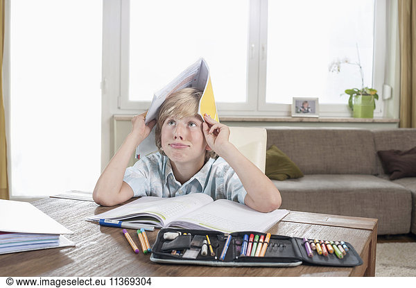 Bored boy with open book on head