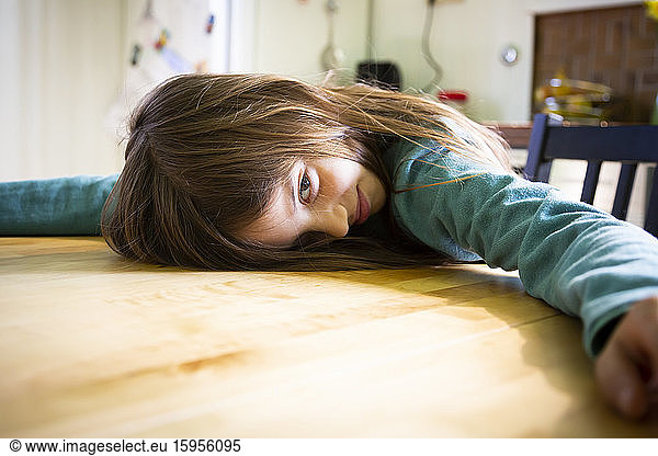 Bored girl lying on kitchen table