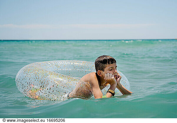 boring white boy swimming in a float in turquoise mediterranean sea
