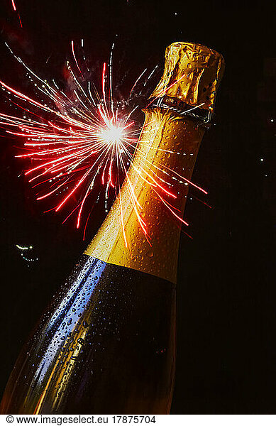 Bottle of champagne against exploding fireworks