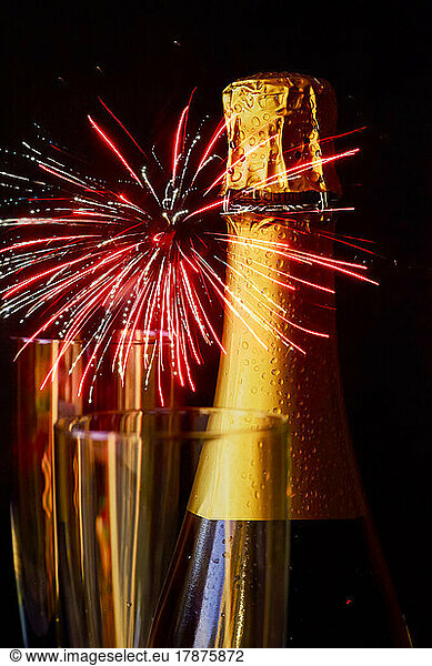 Bottle of champagne against exploding fireworks