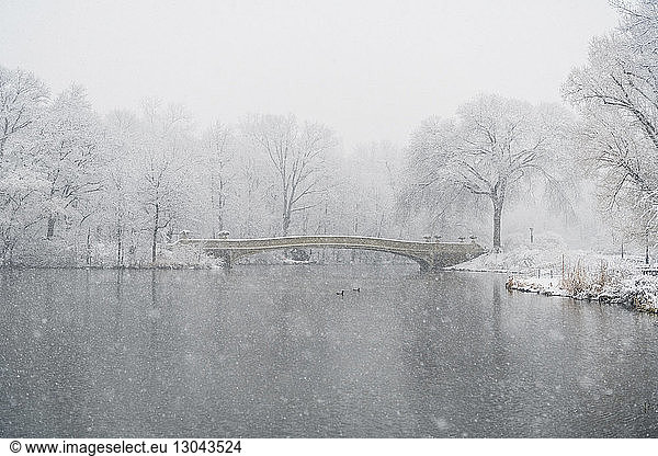 Bow bridge over lake during snowfall
