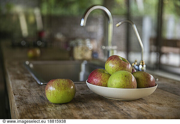 Bowl of apples on wooden kitchen counter