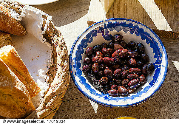 Bowl of dates lying next to basket with bread