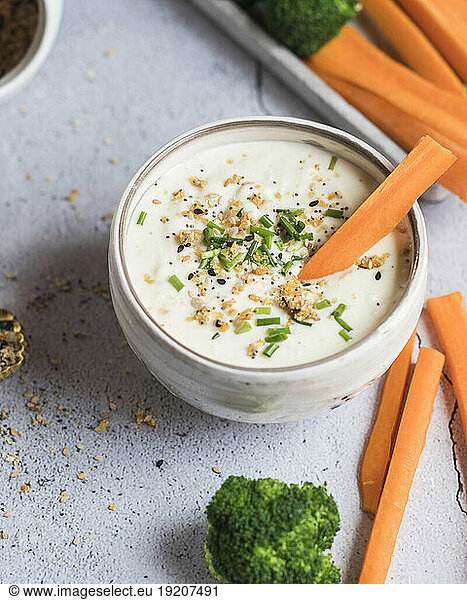 Bowl of feta-honey dip and raw carrots and broccoli