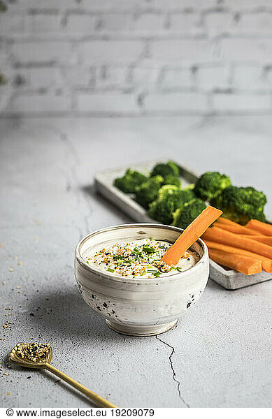 Bowl of feta-honey dip and raw carrots and broccoli
