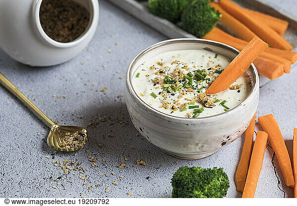 Bowl of feta-honey dip and raw carrots and broccoli