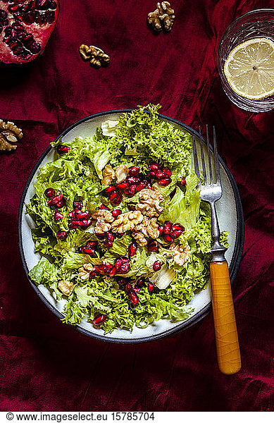 Bowl of green salad with walnuts and pomegranate seed