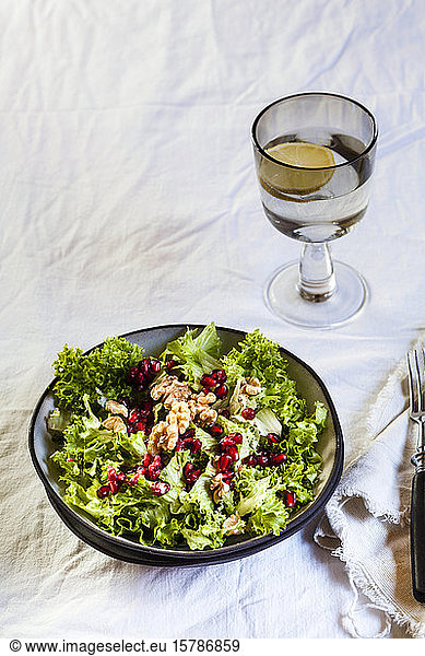 Bowl of green salad with walnuts and pomegranate seed