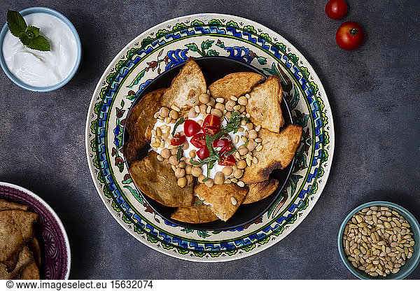 Bowl of Levantine fatteh  with flat bread  tomatoes and chickpeas