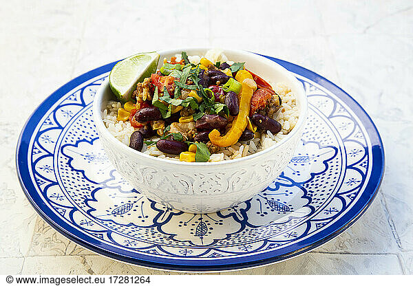 Bowl of Mexican rice with tomatoes  bell pepper  tofu  kidney beans  corn  scallion and lime