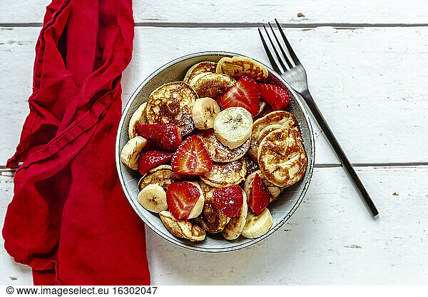 Bowl of mini pancakes with strawberries and bananas