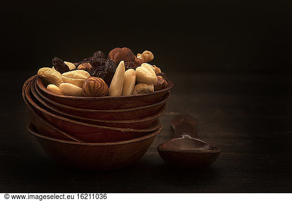 Bowl of nuts and raisins on wooden table  close up