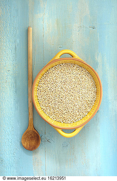 Bowl of pearl barley with wooden spoon on table  close up